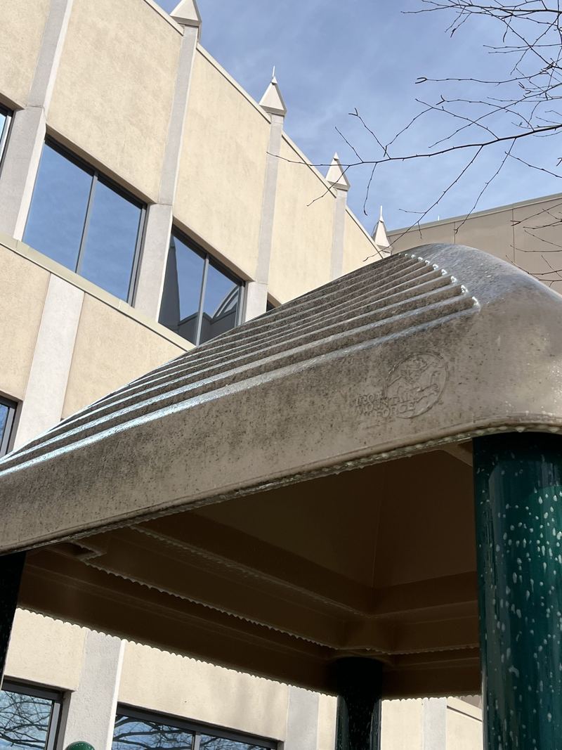 A playground shade canopy at an office building, grey with grime